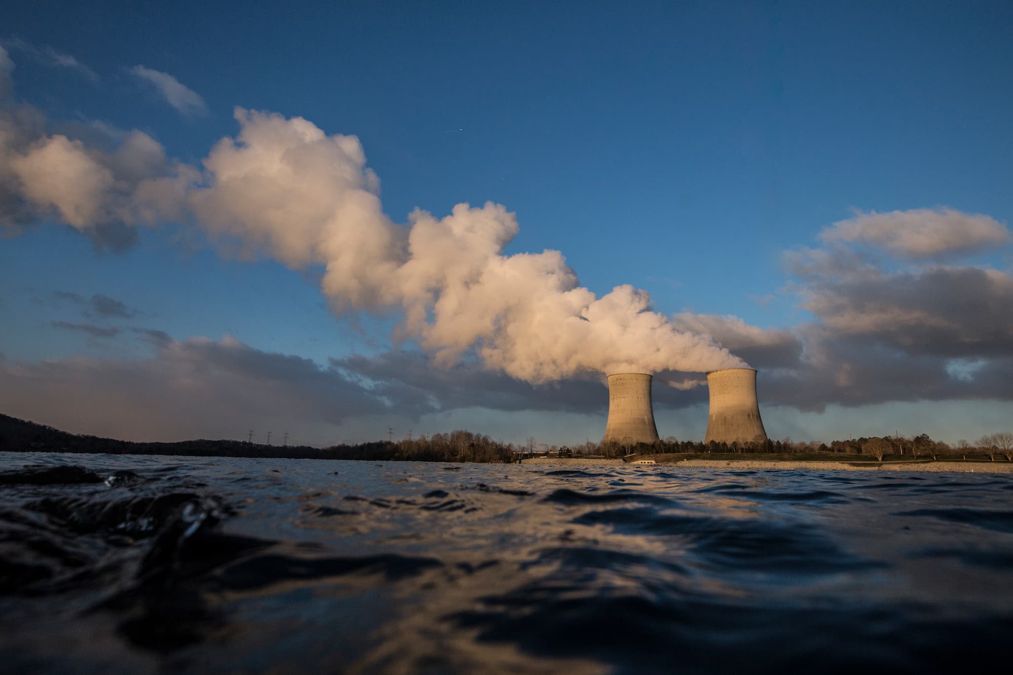 View of two cooling towers from across a river/
