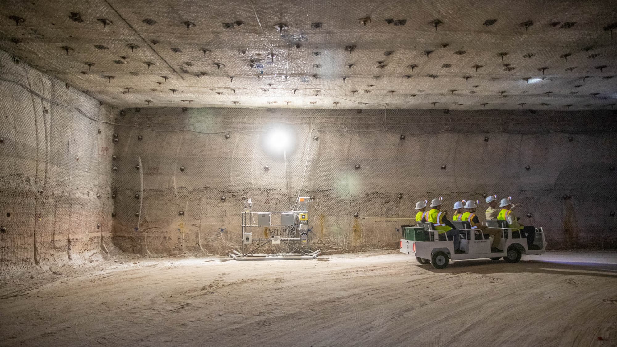 WIPP workers driving cart through underground facility.