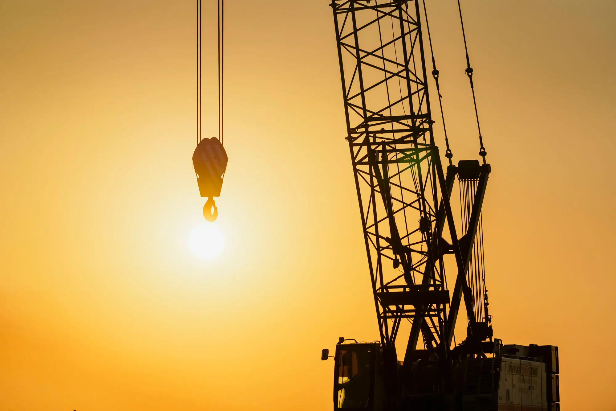 Crane silhouette with orange sunset in hook at Lake Charles