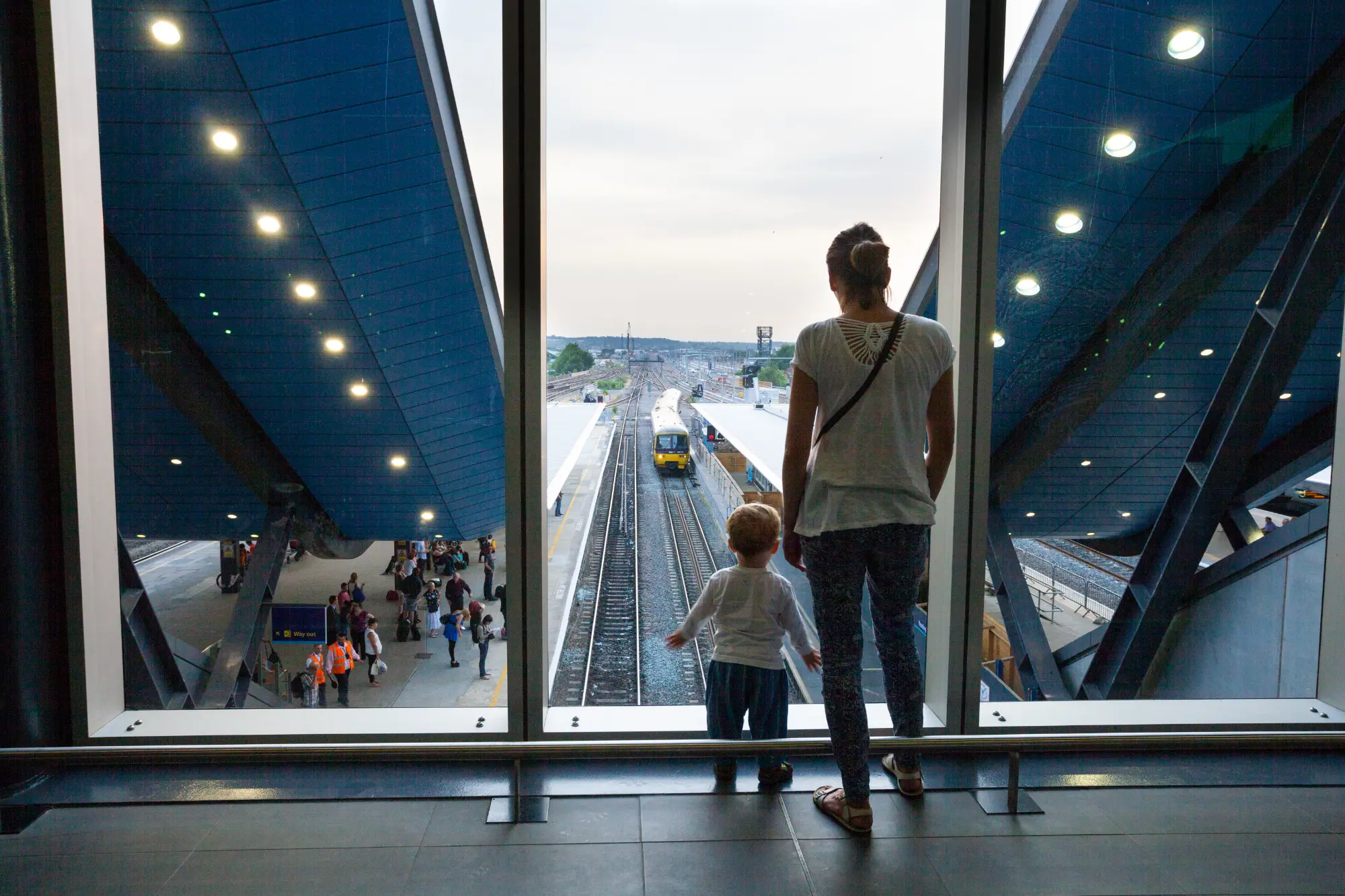 Passengers watch an approaching train into platform 13, from the transfer deck at Reading Station.