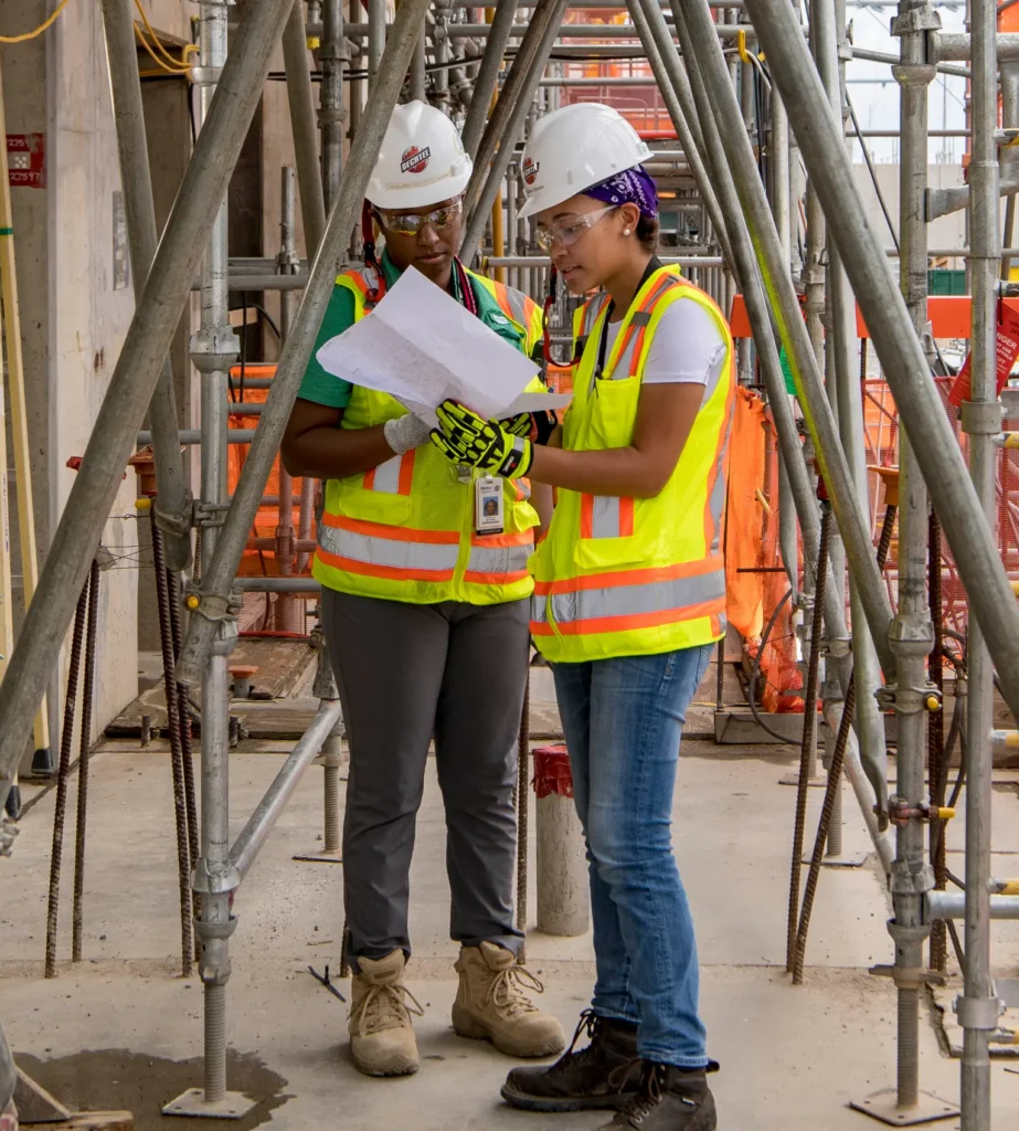Two colleagues review plans for their role on the construction site.